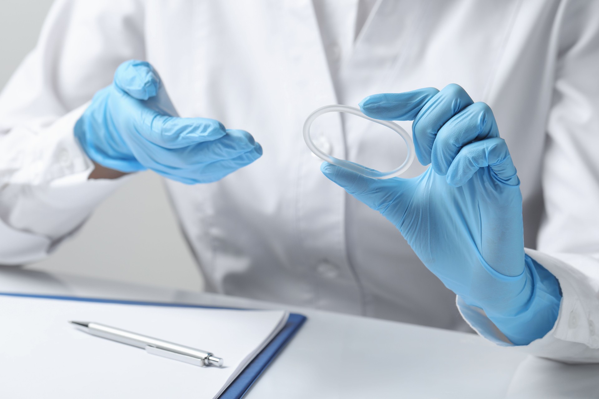 Doctor holding diaphragm vaginal contraceptive ring at table, closeup